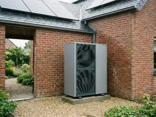Pompe à chaleur au pied d'une maison équipée de panneaux photovoltaïques